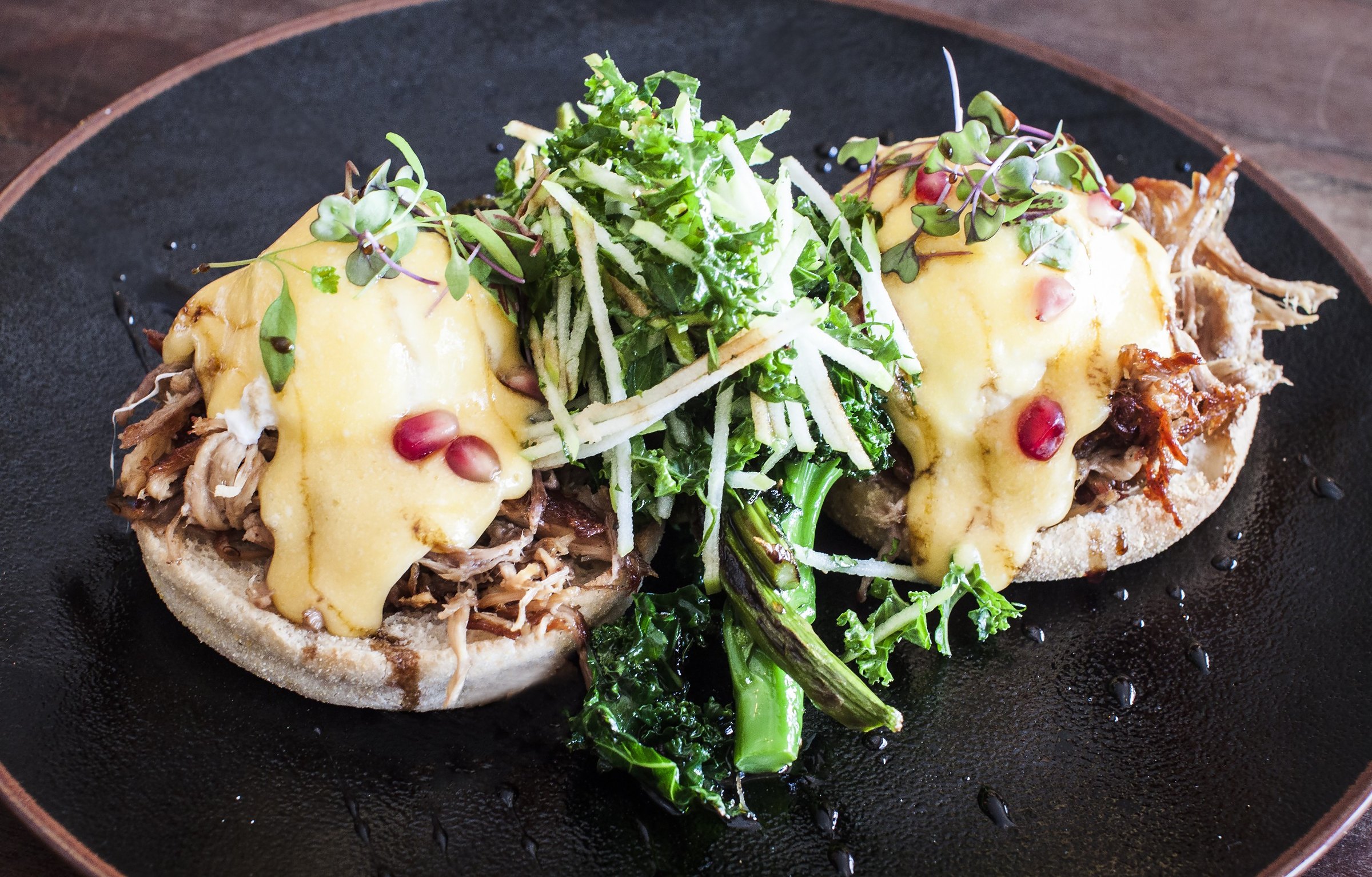 Eggs benedict with hollandaise, greens and pomegranate