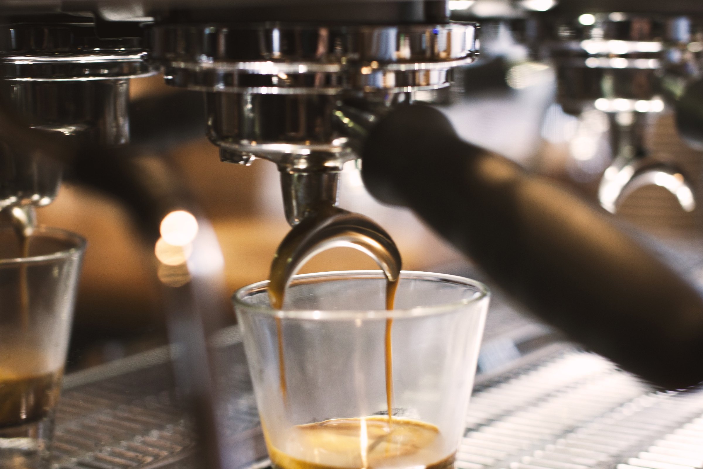 Espresso pouring from the group head into a glass